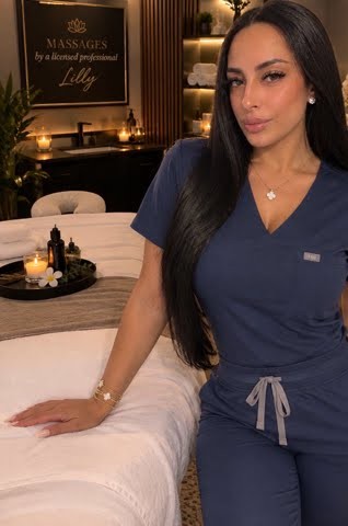 Lilly, smiling, resting a hand on a massage table